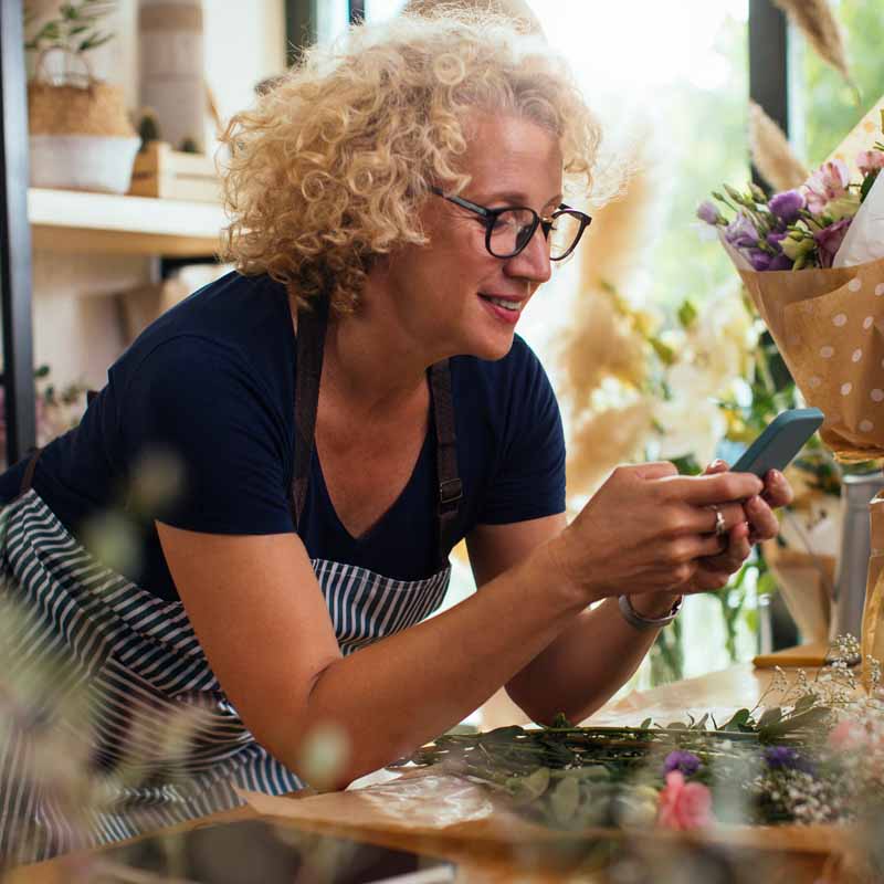 Woman using phone in florist's